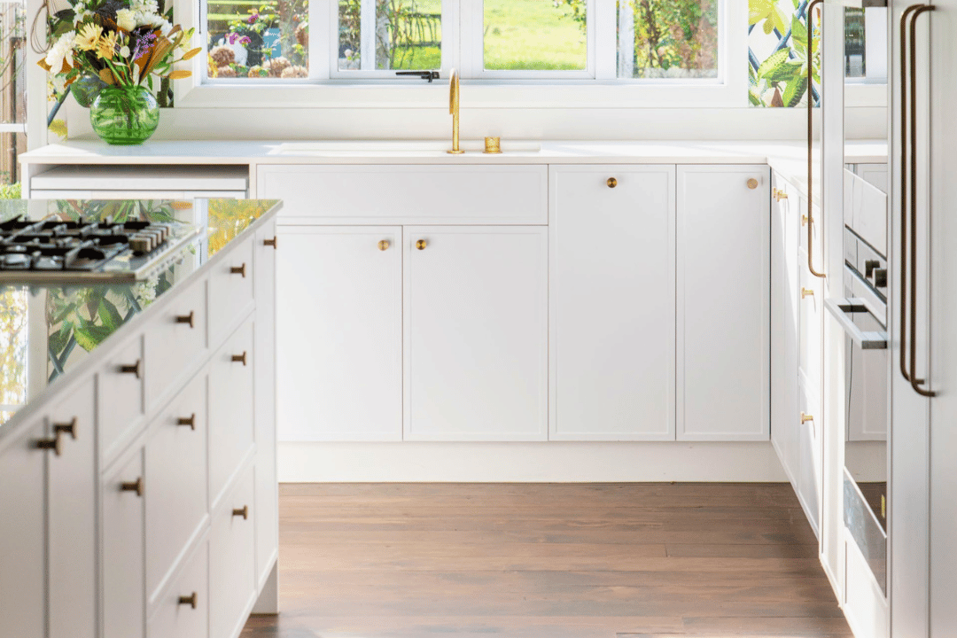 A white minimalist profile kitchen cabinetry with solid brass handles, villa direction